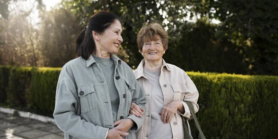 Lächelnde Seniorin mit Begleiterin auf einem Spaziergang im Westerwald